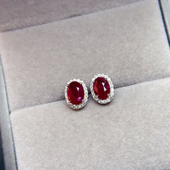 Ruby Oval Cut Stud Earrings in Sterling Silver with Halo Design